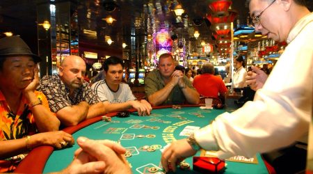 **CORRECTS TO CLARIFY SECOND SENTENCE REMOVES INFORMATION ABOUT CASINOS CLOSING WEDNESDAY **Dealer Patrick Chen collects chips on the poker table as players  look on at the Resorts Atlantic City casino in Atlantic City, N.J., Tuesday, July 4, 2006. Gov. Jon S. Corzine hauled lawmakers in to work on the July Fourth holiday, imploring them to end a budget standoff that has shut down many government services, while Atlantic City casinos fought to keep from being dragged into the dispute. (AP Photo/Mary Godleski)